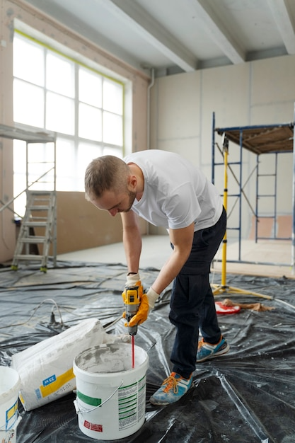 Man mixing cement with drill | The Paint Masters