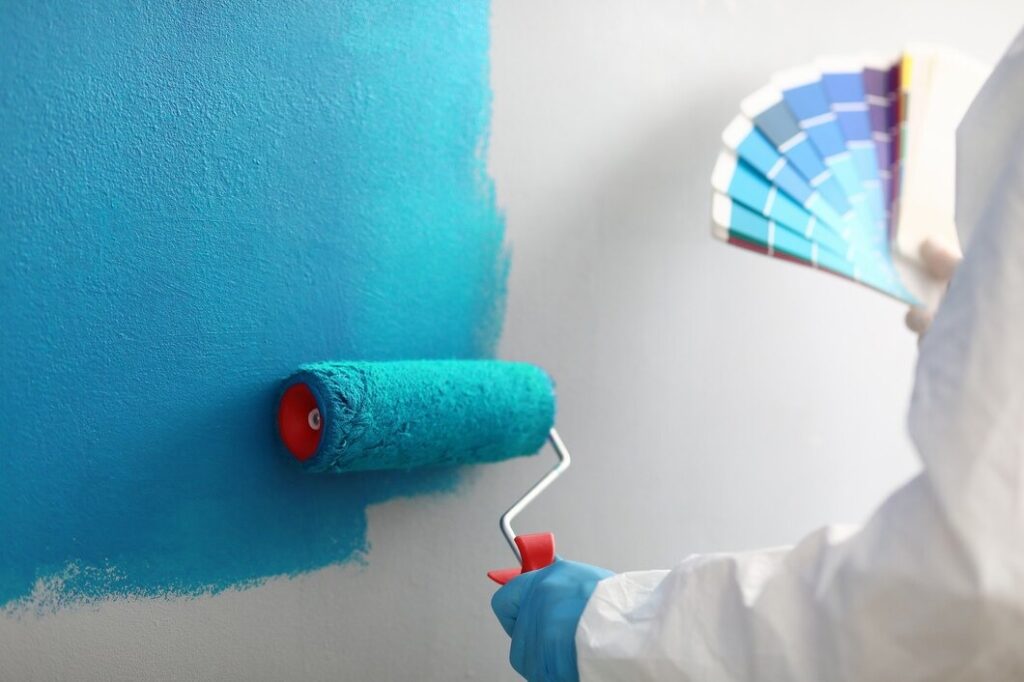 Person painting wall with roller | The Paint Masters